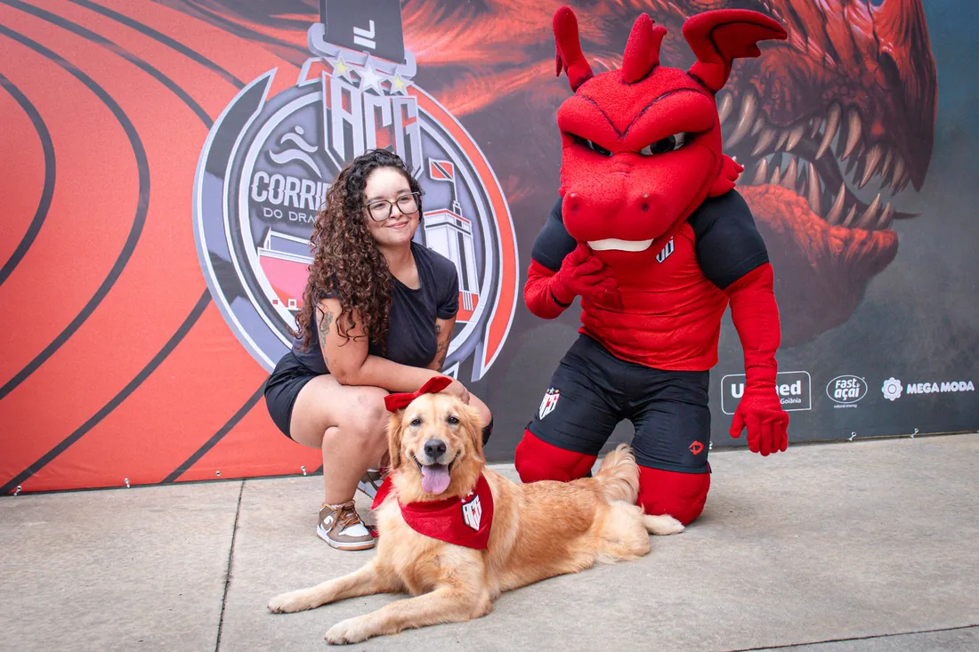 Corredora com seu cachorro e o mascote do Dragão no backdrop oficial